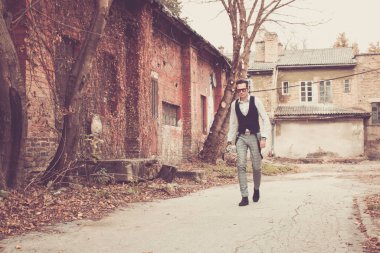 Fashionable man with umbrella walking alone through the old town. 