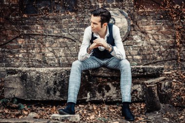 Mid adult retro-styled man looking away and thinking of something while relaxing outdoors. 