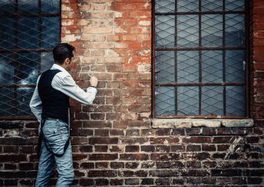 Rear view f retro-styled man writing with chalk on a wall.