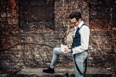 Retro-styled man reading newspaper outdoors.