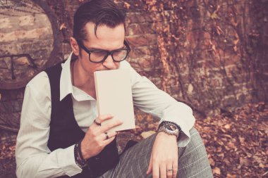 Mid adult man thinking of something while holding a book outdoors. 