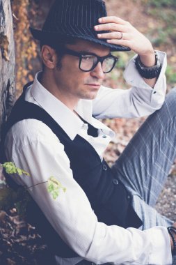 Portrait of pensive well dressed man with fedora hat relaxing outdoors and contemplating.