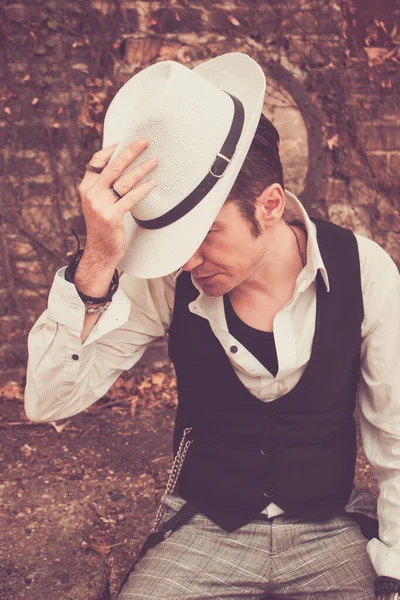 retro styled man tipping fedora hat outdoors.
