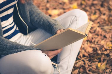Close up of female student learning in nature. Unrecognizable girl reading a book in the park.
