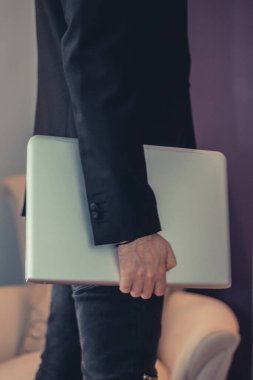 Unrecognizable businessman holding laptop. 