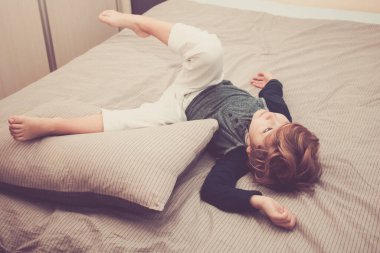 High angle view of bored kid lying down on the bed. 
