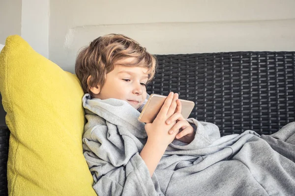 Smiling boy relaxing and reading something on mobile phone.