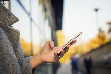 Close up of woman texting on cell phone in the city.