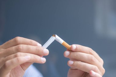 Close up of person breaking cigarette in half. Stop smoking concept. 