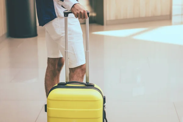 Unrecognizable person with travel bag standing in hotel hallway.