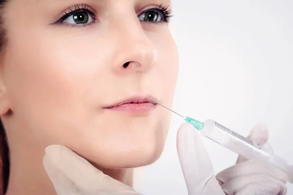 Lip augmentation. Beautiful woman receiving Botox injection in her lips.