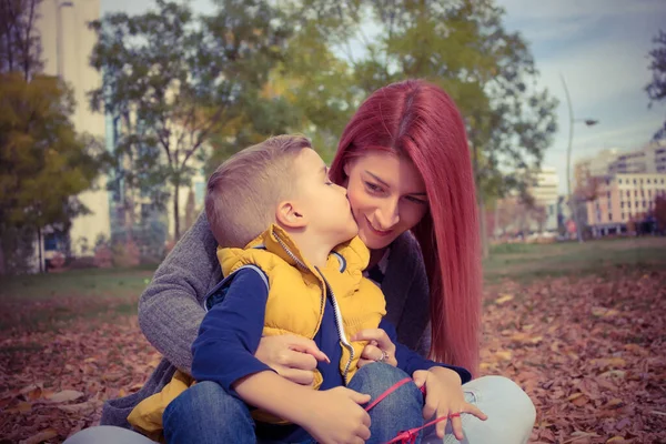 Affectionate son kissing his mother while enjoying in time together at the park.