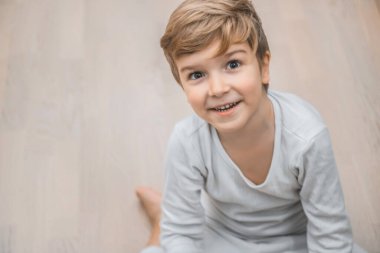 Portrait of happy kid sitting on the floor and looking at camera. 