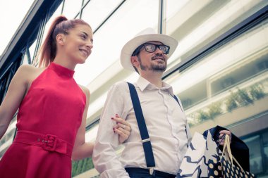 Low angle view of happy couple enjoying in shopping day while walking through the town. 