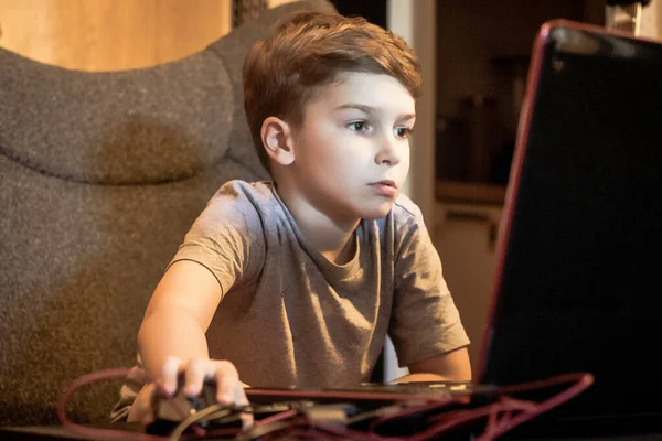 Small kid using computer and playing online games at home. 