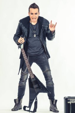 İsyancı gitarist dilini çıkarıp kameraya bakarken boynuz işareti gösteriyor.. 