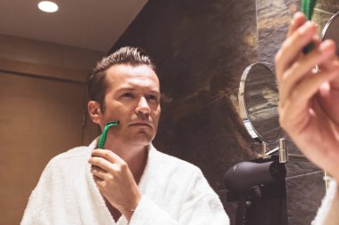 Banyoda jiletle tıraş olan bir adamın aynadaki yansıması.. 