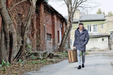 Elinde bavulla caddede yürüyen perişan bir adam..