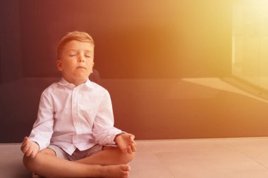 Lotus pozisyonunda meditasyon yapan küçük bir çocuk. Çocuk gözleri kapalı yoga yapıyor.. 