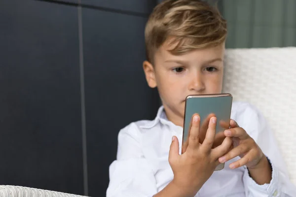 Oyun oynarken cep telefonu kullanan küçük çocuğa yaklaş.