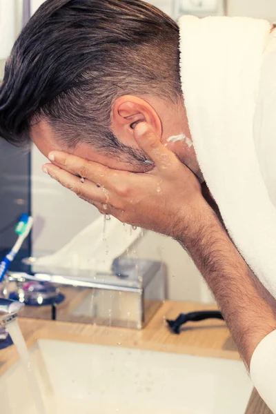 Close up of man washing face in the bathroom.