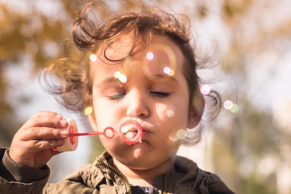 Parkta gözleri kapalı kabarcıklar çıkaran tatlı küçük kız.. 