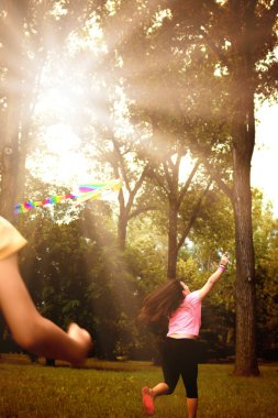 Uçurtmayla koşan ve bahar günü parkta eğlenen bir kızın arka görüntüsü.. 