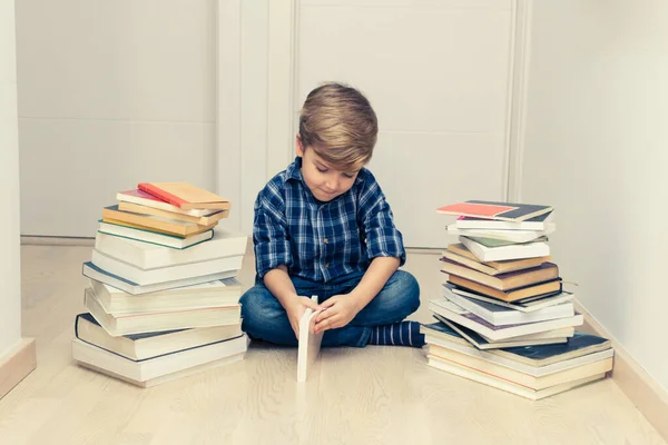 小孩坐在书堆中的地板上学习 — 图库照片