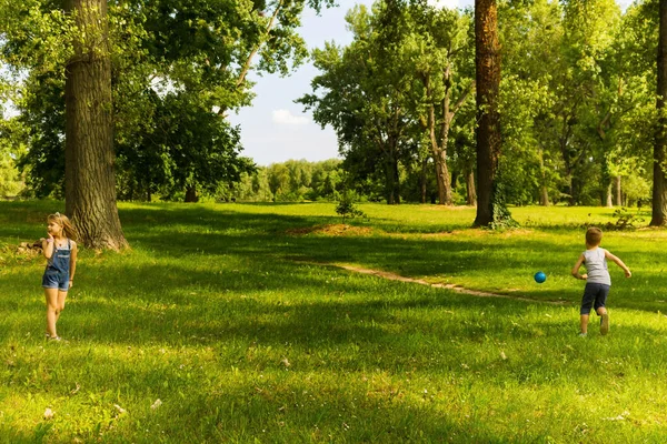 春の日に公園でボールと遊ぶ男の子と女の子 — ストック写真