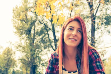 Mutlu kızıl saçlı kızın portresi Sonbaharda gündüz rahatlayan Parkta hayal kuran.