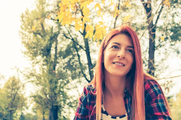 Mutlu kızıl saçlı kızın portresi Sonbaharda gündüz rahatlayan Parkta hayal kuran.