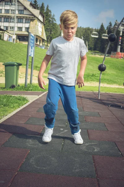 Mały Chłopiec Bawiący Się Placu Zabaw Podczas Gry Hopscotch — Zdjęcie stockowe
