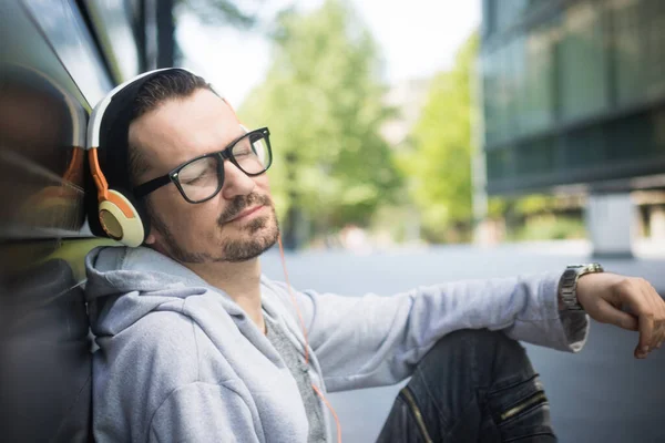 Чоловік Закритими Очима Слухає Музику Над Навушниками Розслабляючись Місті — стокове фото