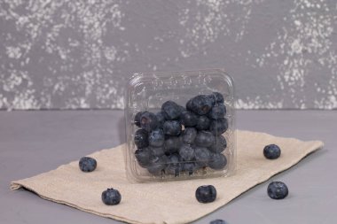 Kırsal kumaşta taze yaban mersini, gri bir arka plan.