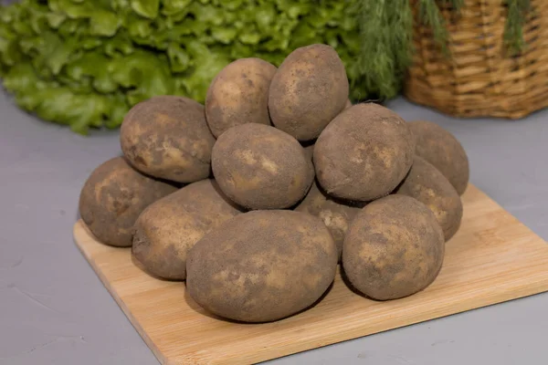 Patatas Frescas Una Tabla Madera Sobre Fondo Ensalada Verde —  Fotos de Stock