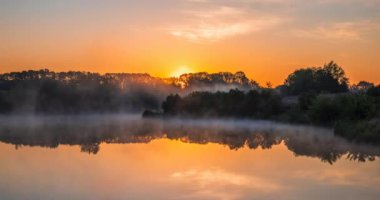 Güneş ufuktan gökyüzündeki renkli bulutların arka planına doğru yükseliyor.