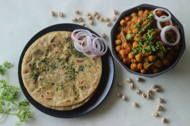 Mükemmel bir şekilde Paratha 'nın etrafında. Susam tohumları ve kişniş yapraklarıyla kaplı buğday unundan yapılmış Hint ekmeği. Beyaz nohut sosu ile servis ediliyor. Bilinen adıyla chole masala. Beyaz arkaplanda çekilen