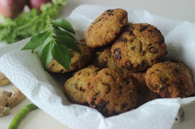 Kodo millet fritters. A crispy fritters made with cooked and mashed kodo millet flour and spices. Disk shaped deep fried evening snack. Commonly known as Kodo millet vada. Shot on white background