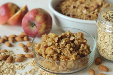 Apple crisp. Cinnamon flavoured apple dessert with lots of chopped apples arranged in a bake dish topped with a mixture of rolled oats, wheat flour, nuts, butter, brown sugar, cinnamon