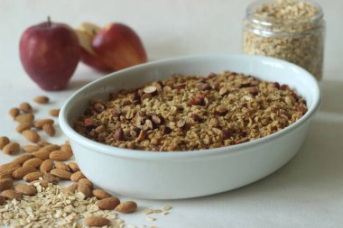 Apple crisp. Cinnamon flavoured apple dessert with lots of chopped apples arranged in a bake dish topped with a mixture of rolled oats, wheat flour, nuts, butter, brown sugar, cinnamon