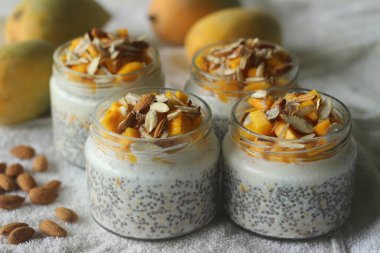 Bir gecede mango ve bademli yulaf. Soğuk, lezzetli, sağlıklı ve kolay bir kahvaltı için kesilmiş mango, badem ve bal ile servis edilen sütlü yulaf ve chia tohumlarından yapılır..