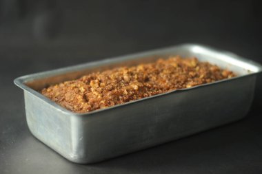 Kepekli un ve hindistan cevizi yağından yapılmış muzlu ekmek. Kıtır kıtır bir üst için tarçın, şeker ve cevizle pişirilmiş. Dikdörtgen bir ekmek tenekesinde servis edilen fırından yeni çıkmış. Koyu arkaplanda çekilen