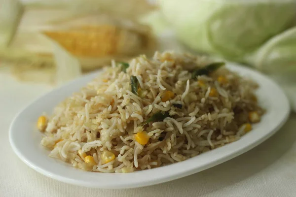 Cabbage corn fried rice. A tasty rice dish with sauteed cabbage and corn flavoured with garlic. A quick meal option with precooked basmati rice. Shot with cabbage and corn in the background.