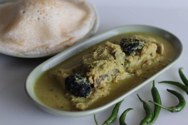 Kerala usulü, hindistan cevizi bazlı körili balık. Pirinç zıpzıp ile servis ediliyor. Kerala 'da genellikle Appam ve balık körisi denir. Beyaz arkaplanda sarı renkli körili balık.