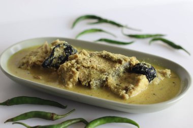 Kerala usulü, hindistan cevizi tabanlı Pomfret balıklı köri. Beyaz arkaplanda sarı renkli körili balık.