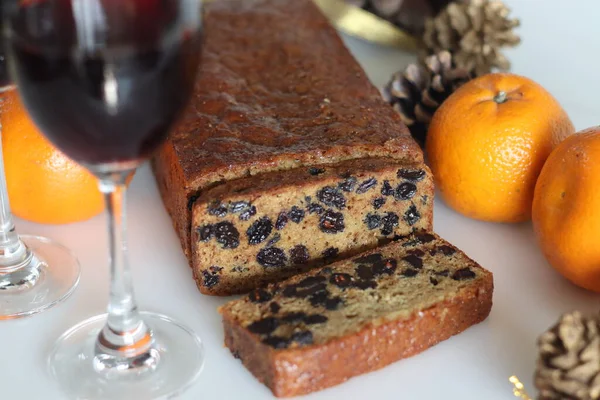 Slices of boiled fruit cake. An easy fruit cake with no alcohol. Made using dry fruits boiled in orange juice. Shot on white background along with red wine and oranges.