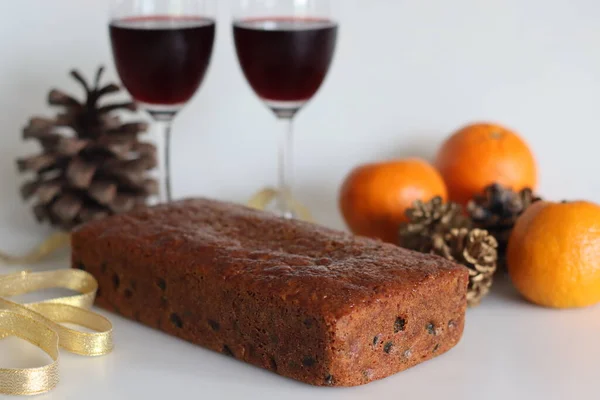 Boiled fruit cake with orange juice. Easy fruit cake with no alcohol. Made using dry fruits boiled in orange juice. Shot on white background along with red wine and oranges.