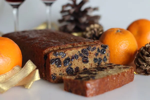 Slices of boiled fruit cake. An easy fruit cake with no alcohol. Made using dry fruits boiled in orange juice. Shot on white background along with red wine and oranges.
