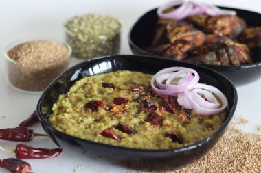 Kodo darı ve mung fasulyesi mercimeği ile bir demlik. Hindistan 'da kodo darı khichdi olarak bilinir. Kızarmış uskumru balığı ve soğan halkalarıyla servis edilir. Beyaz arkaplanda çekilen.