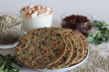 Bajra metil thepla. İnci darı unundan yapılmış Hint düz ekmeği, çemen yaprağı, susam tohumu, yoğurt ve baharat. Yoğurt ve baharatlı sarımsak sosuyla servis edilir. Beyaz arkaplanda çekilen.